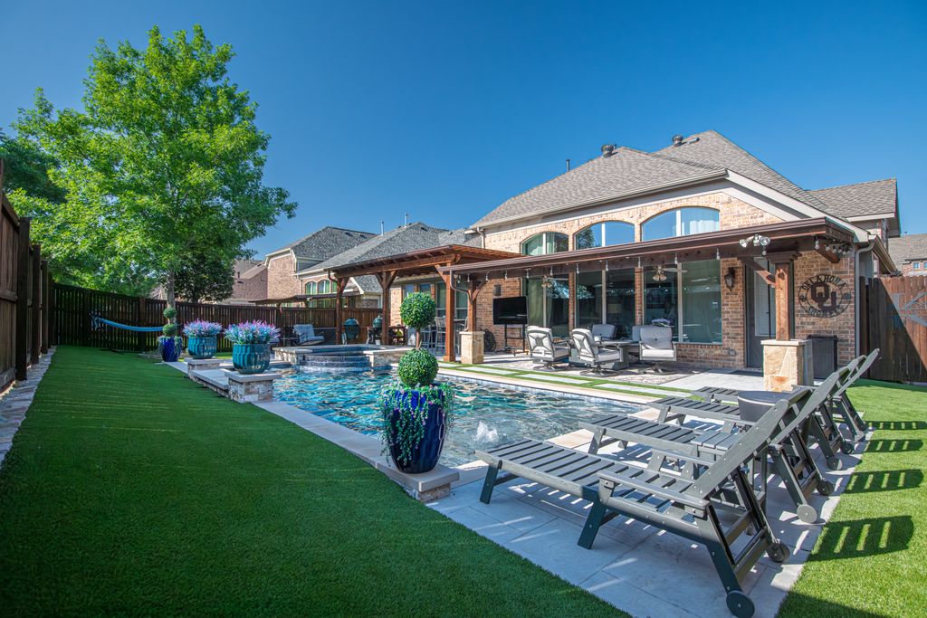 Elegant backyard in Roanoke, Texas with a modern swimming pool, deck chairs, and lush greenery.
